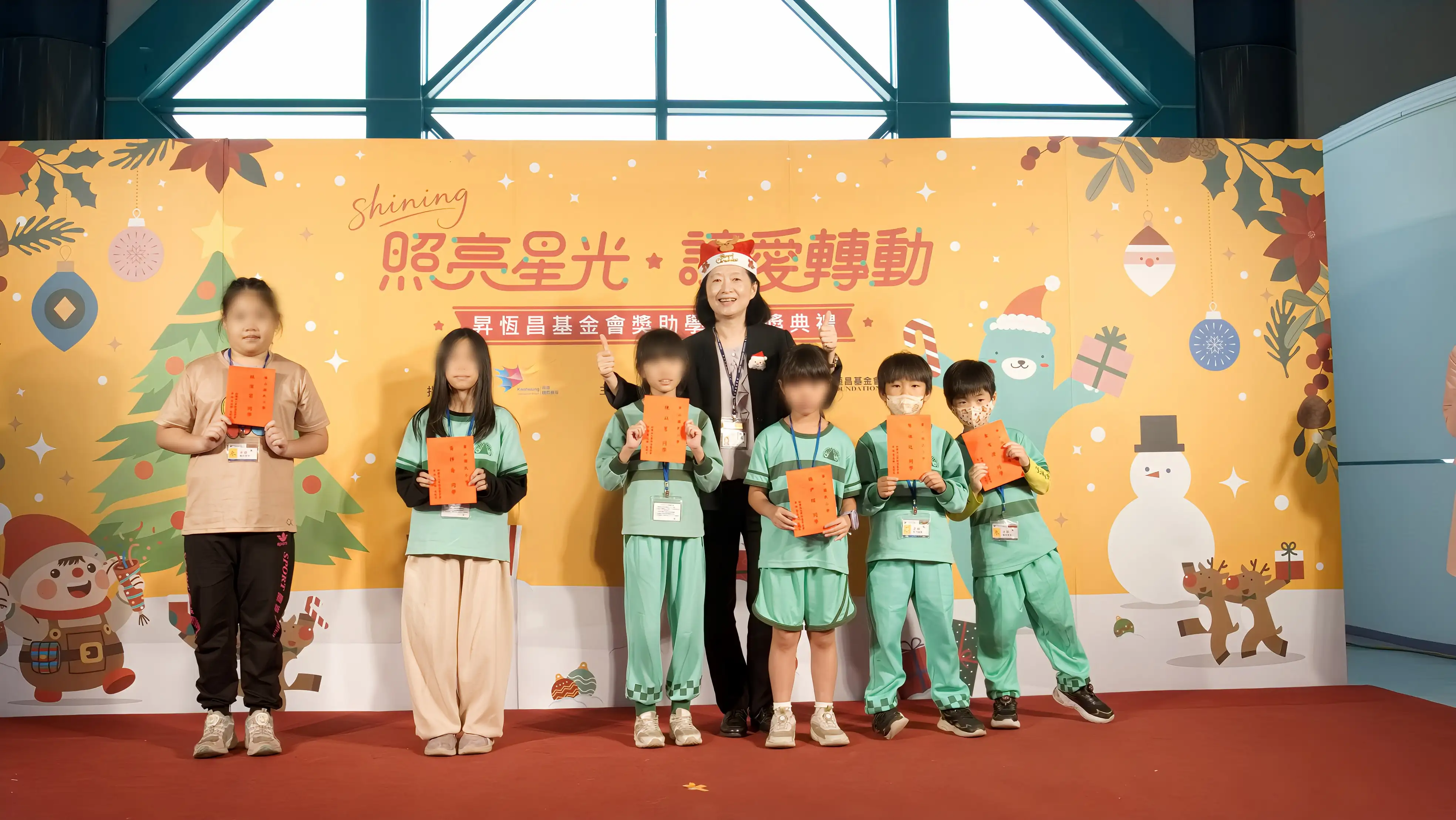 高雄國際航空站主任王郁珍（戴聖誕帽者）頒發獎助學金勉勵學童，場面溫馨。（昇恒昌基金會提供）