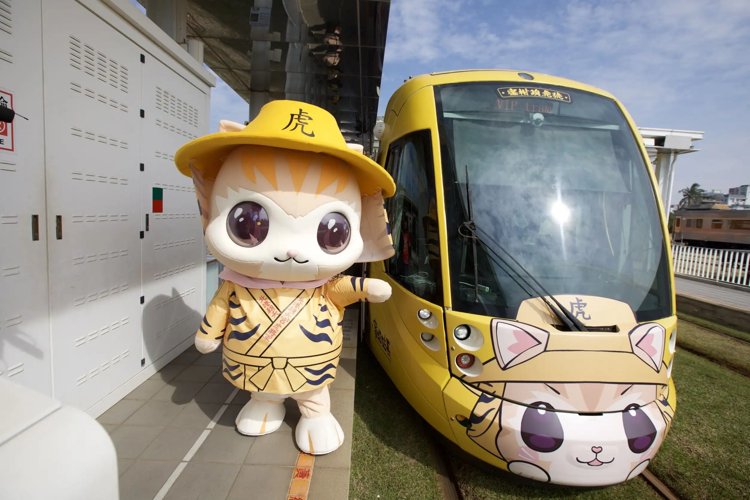 蜜柑站長化身萌虎造型，與「蜜柑萌虎平安號」彩繪輕軌同框亮相，吸睛又討喜，為旅客帶來滿滿福氣與療癒感。(圖/高雄市政府提供)
