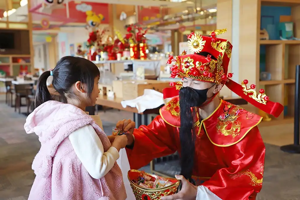 和逸飯店台南館春節活動中，財神爺與小朋友互動發送糖果，營造歡樂年節氣氛。(和逸飯店台南館提供)