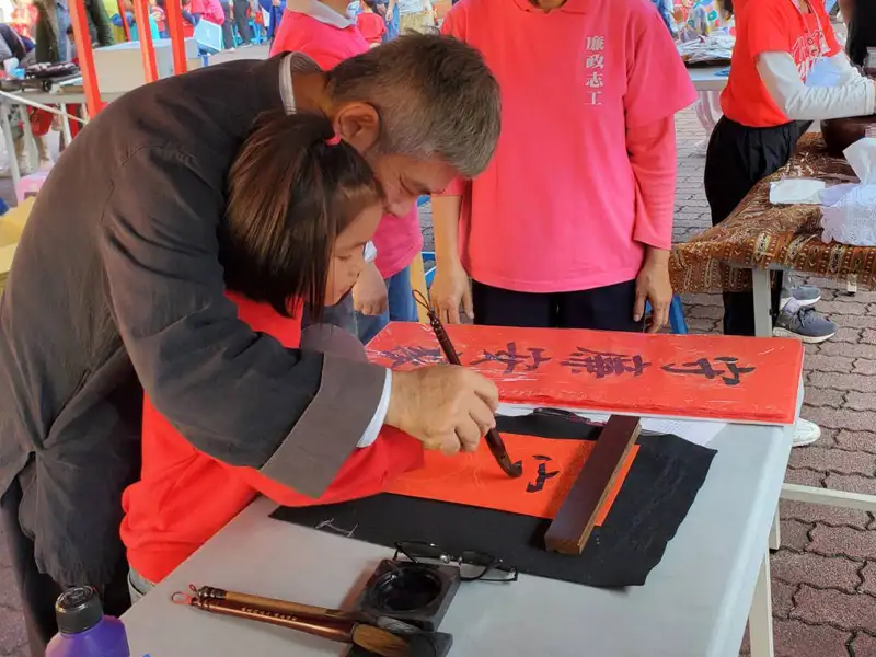 廉政宣導舉辦揮毫贈春聯活動，小朋友開心與書法老師共同展示「守廉安家」春聯。(記者劉美祺翻攝)