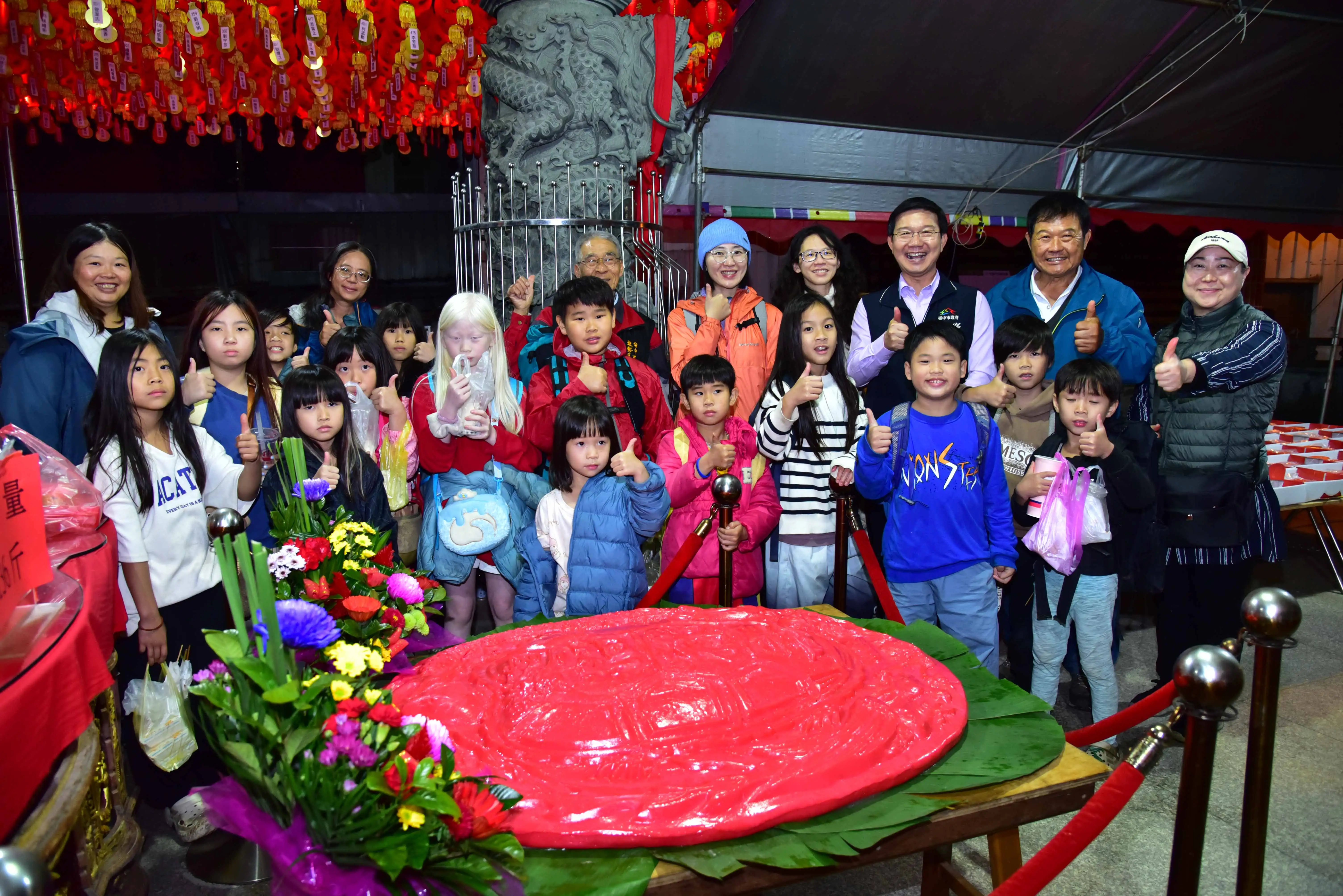 台中東勢新丁粄節鬪粄活動中，泰安宮製作重達136斤的大紅粄亮相，不論花紋設計或份量皆相當吸睛，吸引民眾與親子駐足觀賞並合影留念。(圖/台中市政府提供)