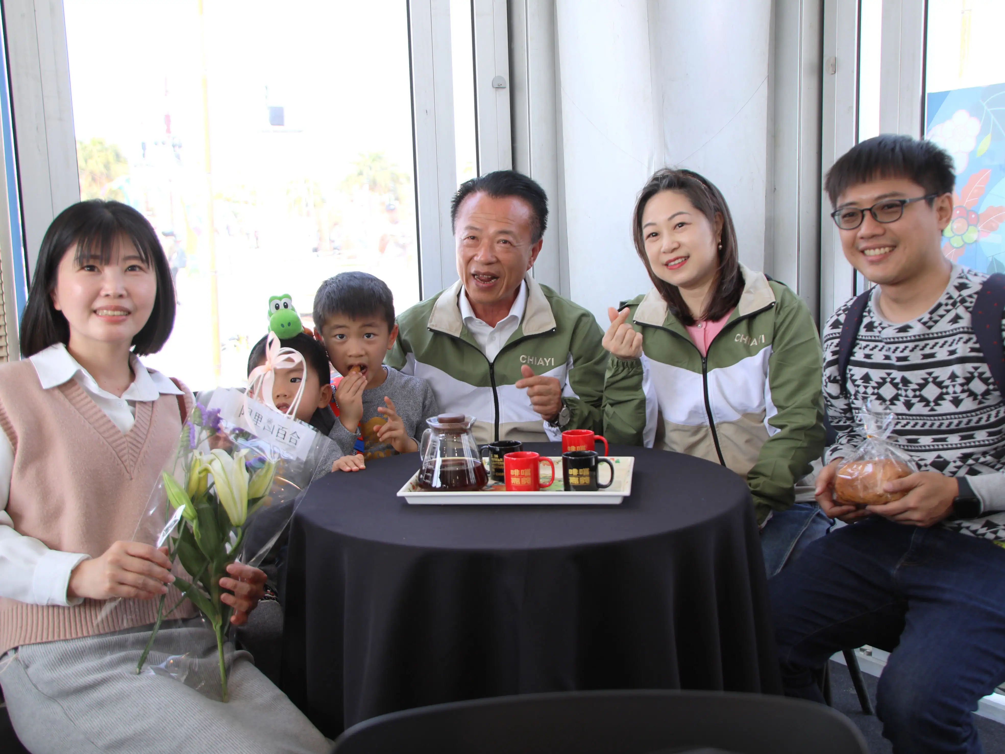 嘉義縣長翁章梁(中)於白色情人節現身台灣燈會「啡嚐嘉義館」，與民眾互動合影並贈送象徵祝福的阿里山百合花束，為燈會活動增添浪漫氣氛。（圖/嘉義縣政府提供）