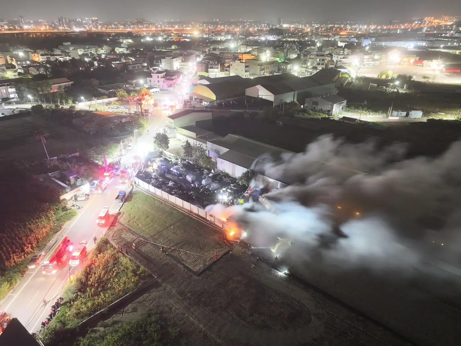 台南仁德回收工廠全面燃燒，濃煙與火勢吞噬鐵皮建物，消防人員全力灌救。。(圖/台南市消防局提供)