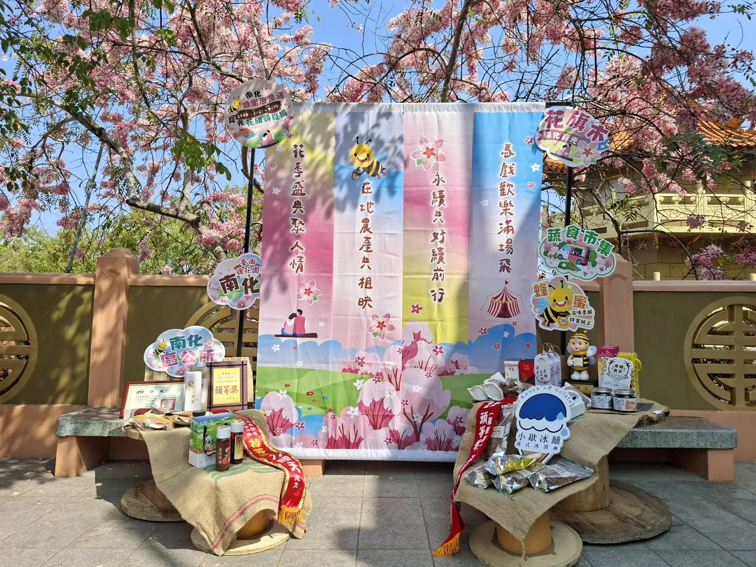 南化「糖蜜浪漫遇」活動現場設置花旗木主題拍照區與在地農特產品展示，展現蜂蜜與黑糖等特色產業魅力。（圖/台南市農業局提供）