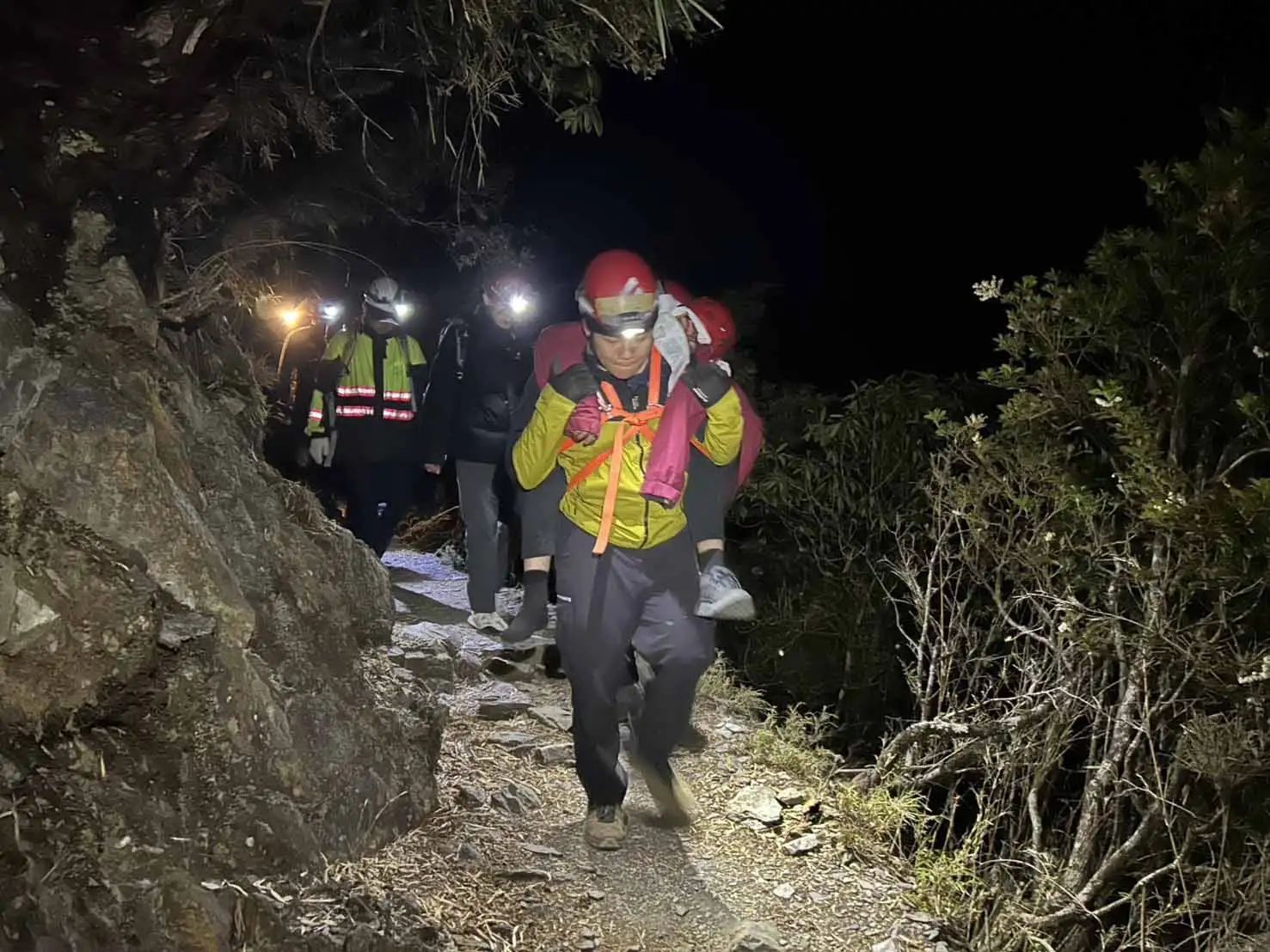 警消與搜救人員深夜上山救援，成功將跌落邊坡的登山客背負下山送醫。（圖/竹崎分局提供）