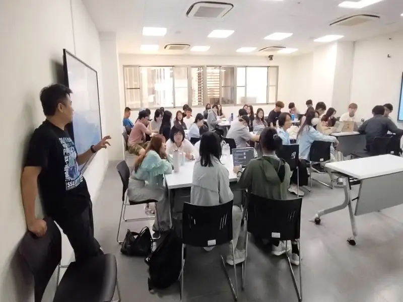 上課的六十位學生分成四組進行團體研究和報告,成四組進行團體研究和報告,太太葉蘊慈上台報告,蔡榮勳台下補充。(圖/冠軍木瓜牛奶蔡榮勳提供)