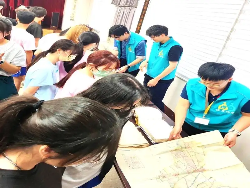 臺南市佳里地政事務所人員向國立北門高級中學學生展示日治時期地政歷史簿冊與地籍圖,透過實體資料解說土地登記沿革,讓學生近距離觀察早期地政紀錄樣貌與應用。(圖/台南市政府地政局提供)