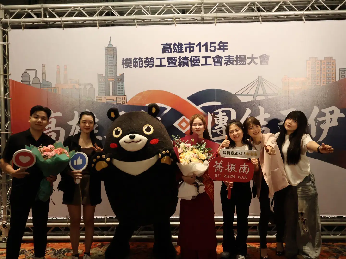 高雄市模範勞工暨績優工會表揚大會，獲獎者與親友及吉祥物合影留念，分享榮耀時刻。（圖/高雄市政府提供）