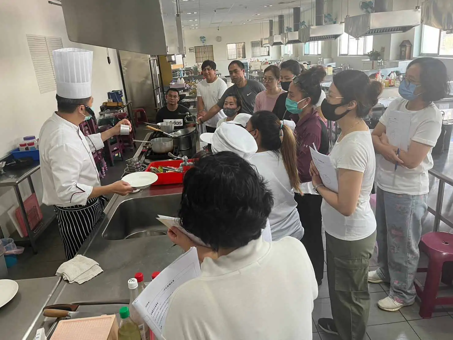 職訓課程中講師示範料理技巧，學員專心學習並進行實作。（圖／勞工局提供）