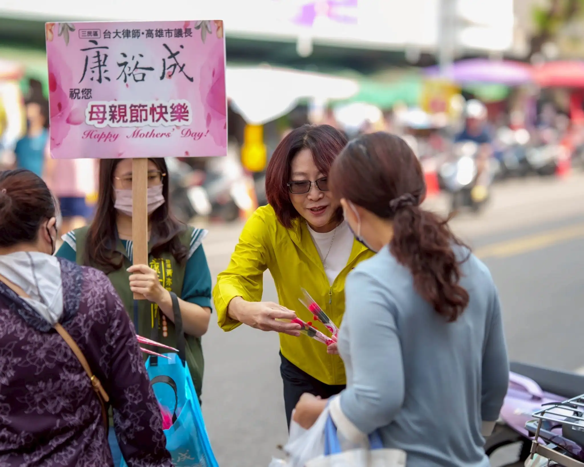 高雄市議長康裕成前往三民區陽明市場贈送康乃馨，提前祝福媽媽們母親節快樂，受到民眾熱情歡迎。（記者吳文生攝）