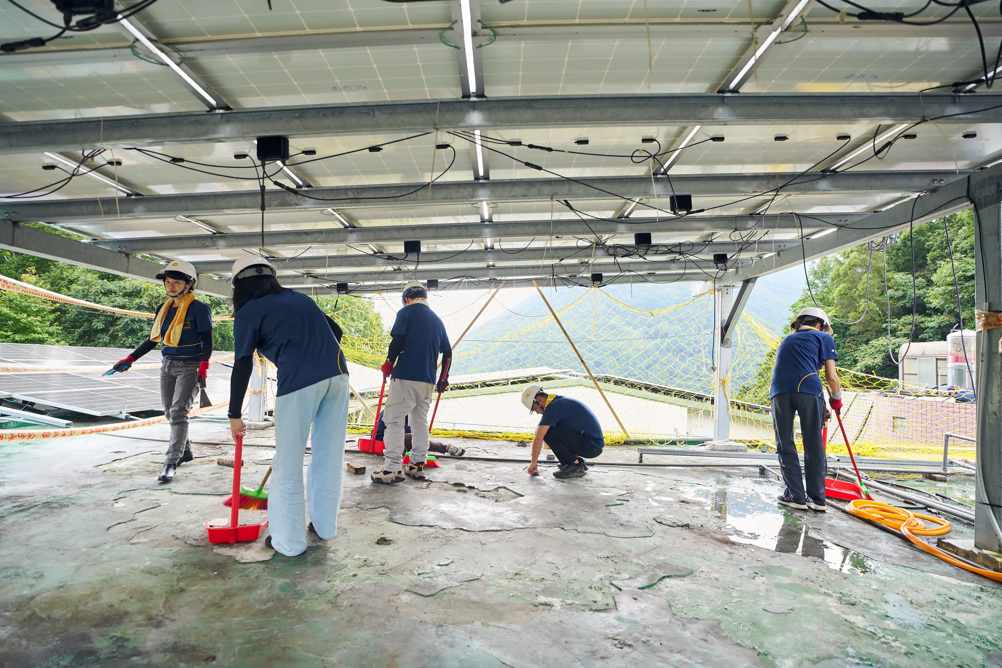 遠雄志工們除去破損的PU防水層、清掃地面，以便後續施作頂樓防水工程。