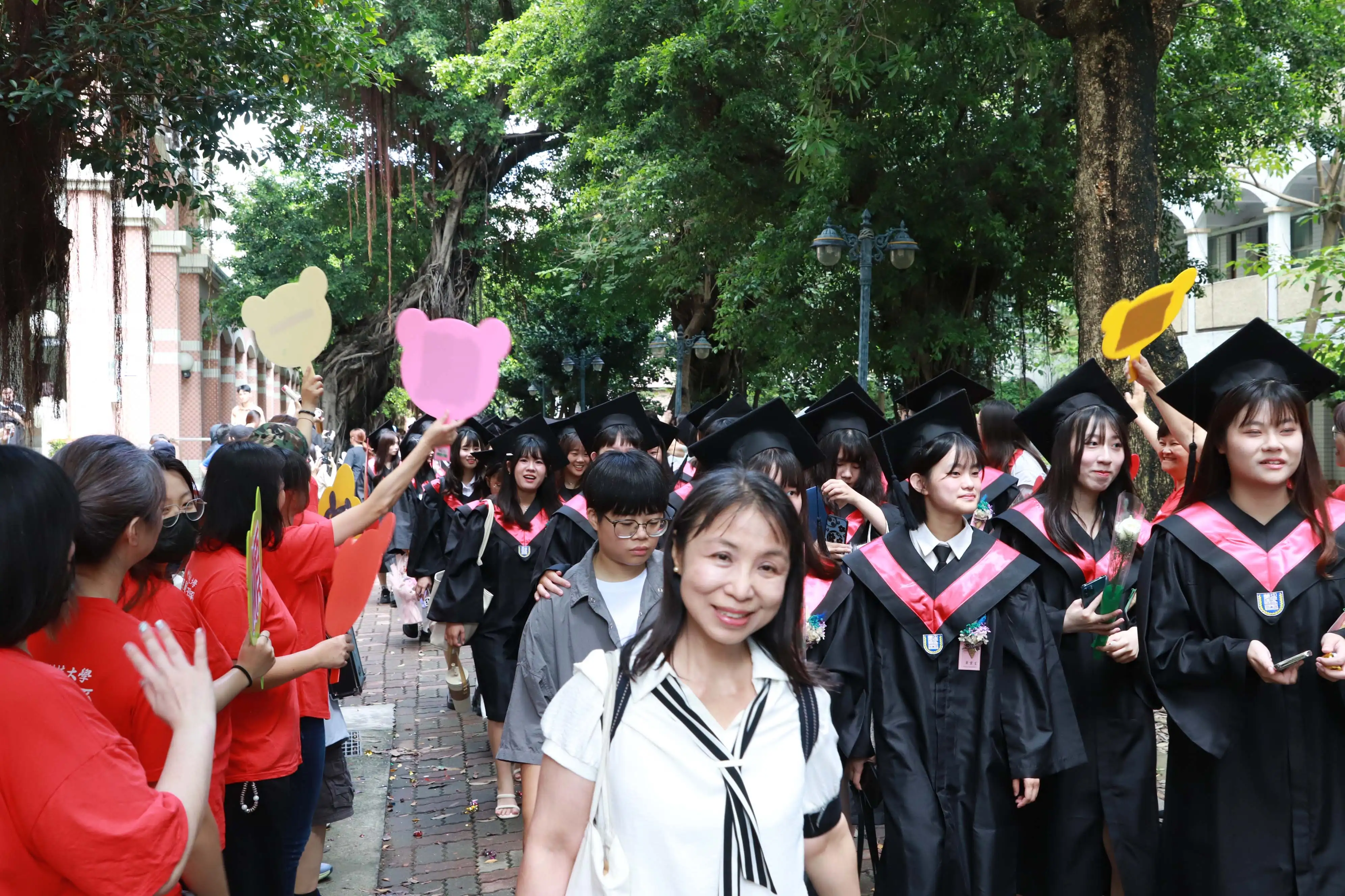 畢業生身穿學位服展開校園巡禮，師長及學弟妹夾道揮手歡送、獻上祝福，為畢業生留下充滿感動與回憶的校園時光。(記者張振興攝)