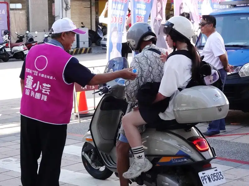童小芸服務團隊於路口開講現場發送瓶裝水，向往來民眾表達關懷，在炎炎夏日送上清涼與問候，獲得不少民眾肯定與支持。(圖/記者范繼如攝)