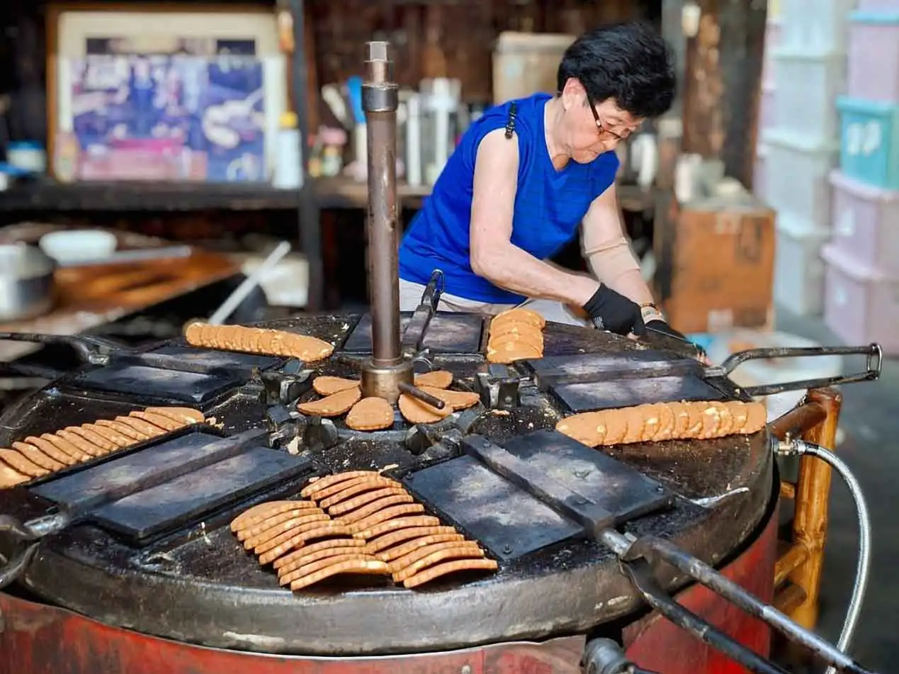 老式煎餅機烤餅的樣子，令不少人佇足觀賞，圖為第三代製餅的情形。（圖/張耘書拍攝)