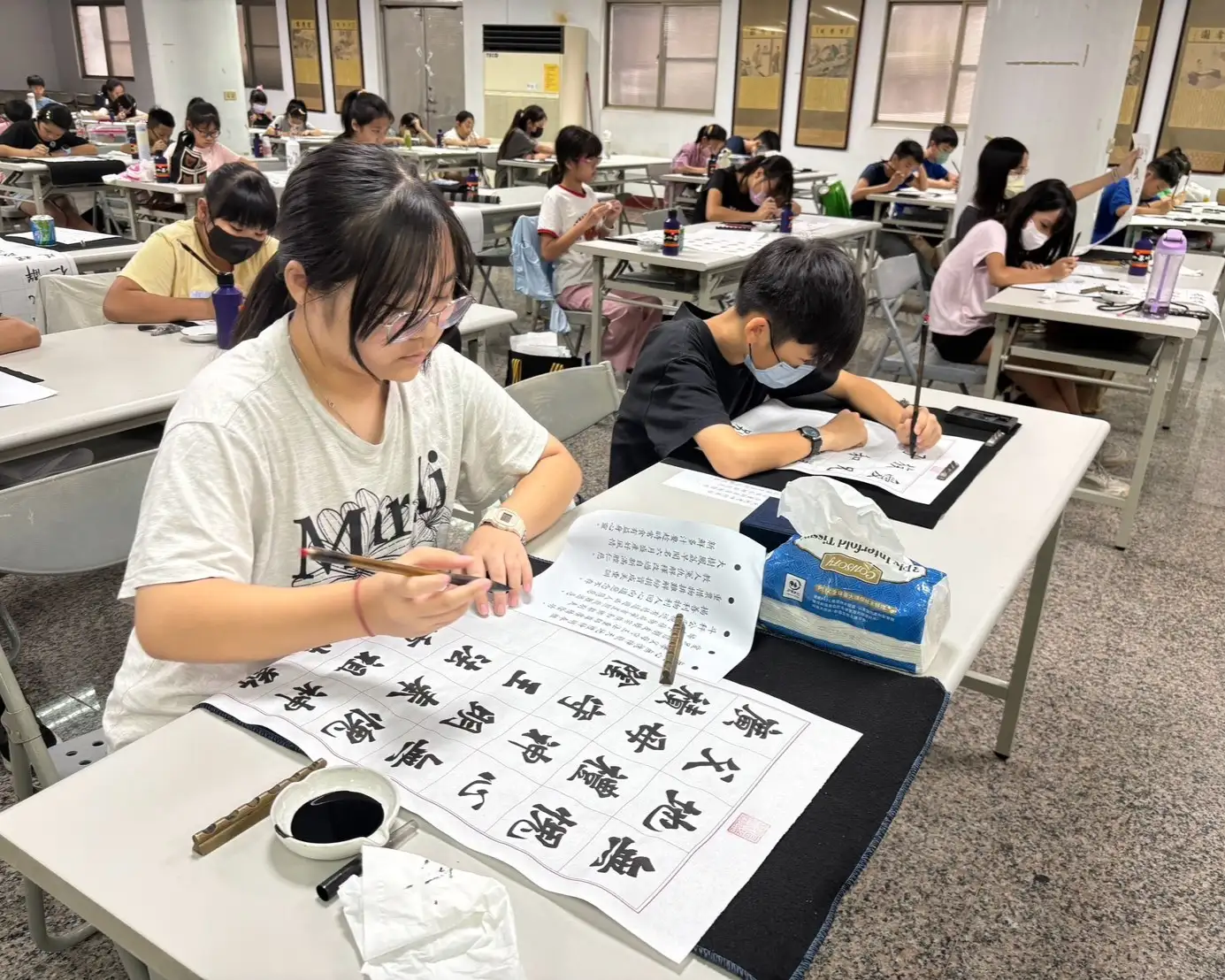 決賽現場學生凝神揮毫、專注創作，展現平日勤練書法的成果與沉穩台風。（高雄東照山關帝廟提供