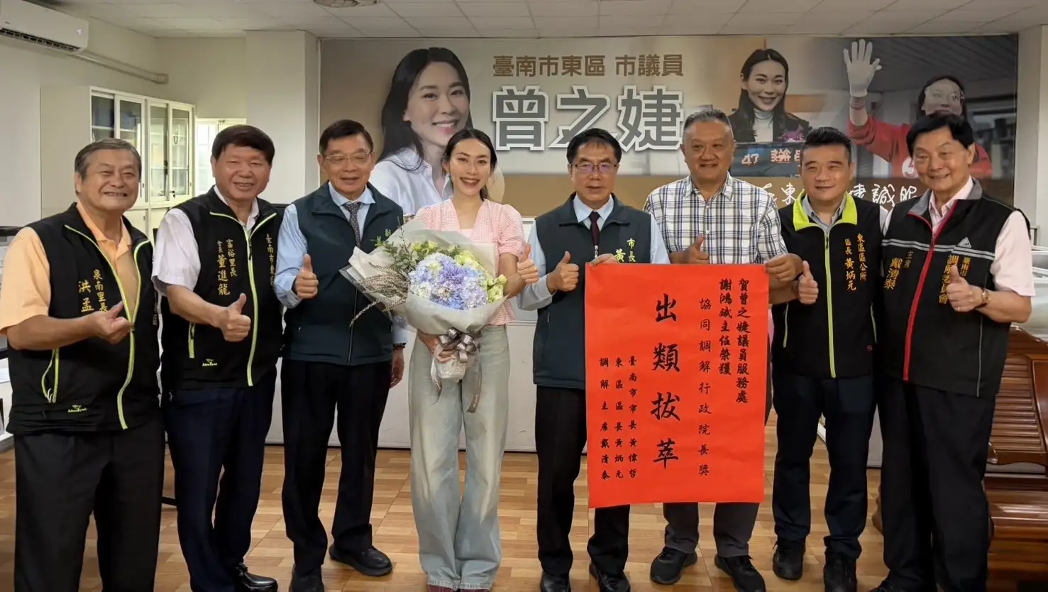 台南市議員曾之婕(左四)服務處主任謝鴻斌(右三)深耕調解工作23年，連續7年獲行政院長獎。市長黃偉哲等人前往服務處致贈「出類拔萃」紅榜祝賀。(曾之婕服務處提供)