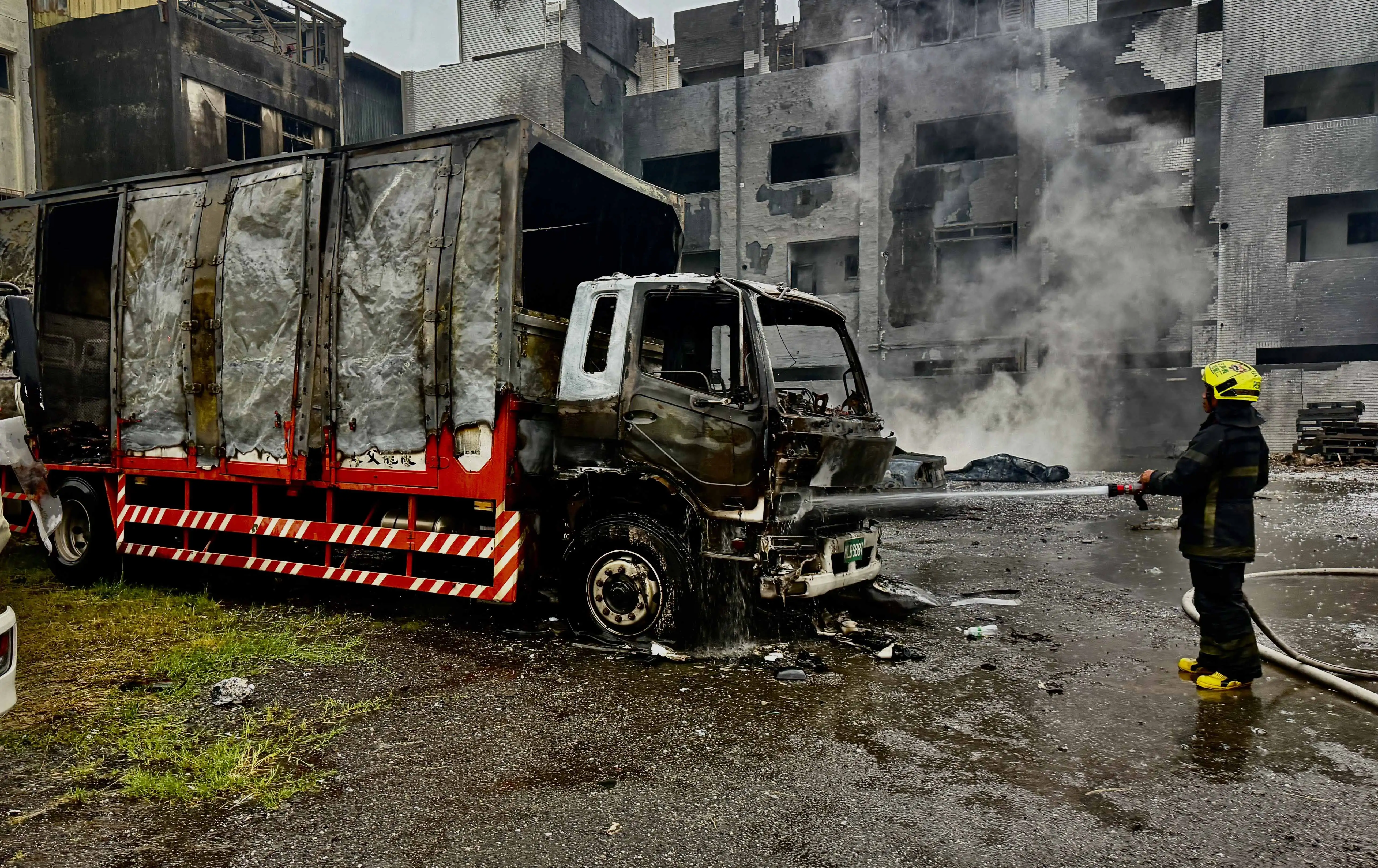 台南市安南區海佃路一處空地22日凌晨發生廢棄物火警並引發爆炸，猛烈火勢波及救災車輛及周邊建物，消防人員持續灑水降溫、處理殘火。（台南市消防局提供）