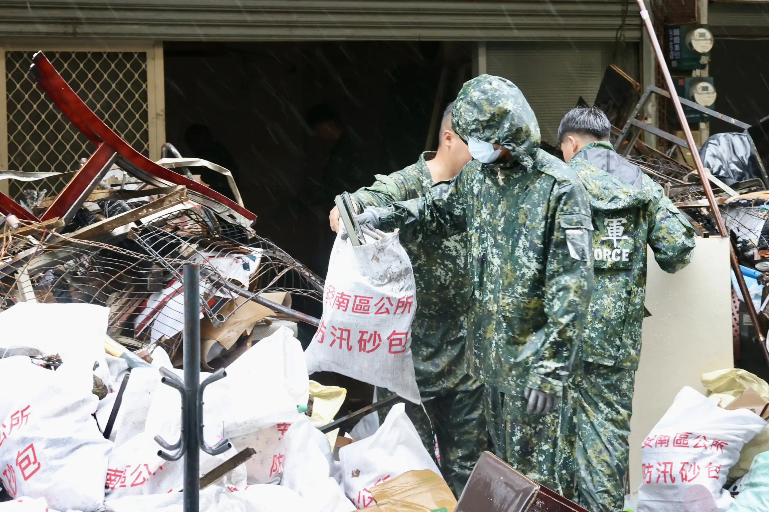 國軍官兵冒雨投入安南區海佃路火災災區復原工作，協助受災住戶搬運、清理遭火勢及爆炸波及的家具與廢棄物。（台南市政府提供）