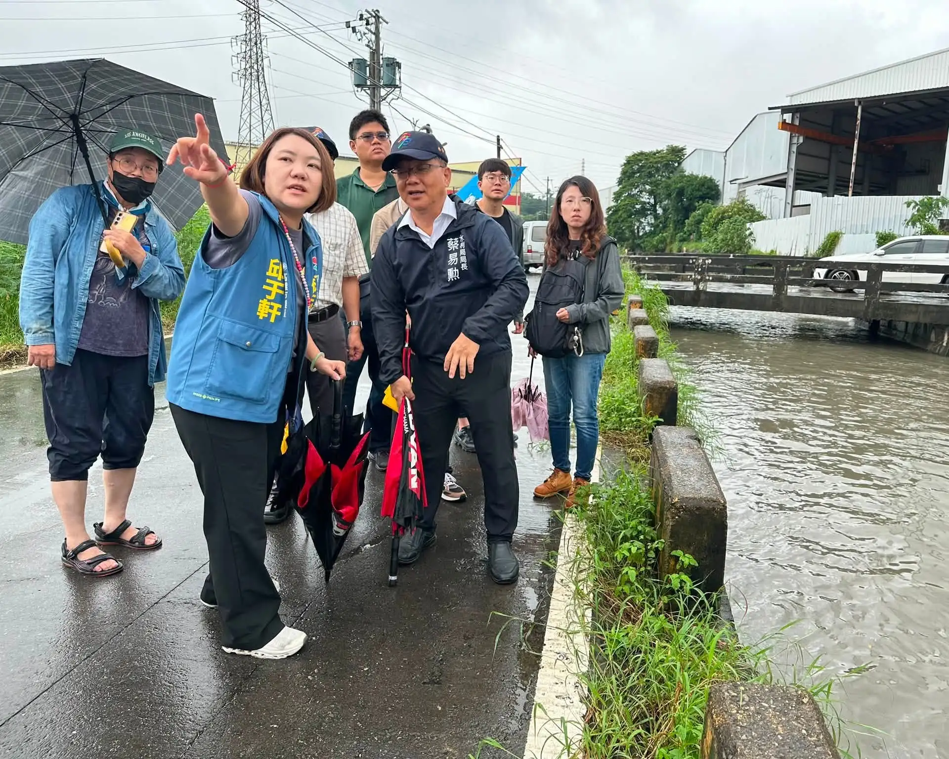 連日豪雨造成大寮區過溪里道路3日出現明顯龜裂，市議員邱于軒會同過溪里長陳秀英及水利局長蔡易勳前往現場會勘，考量路基受損及塌陷風險，要求先行封閉道路並儘速搶修。（邱于軒團隊提供）