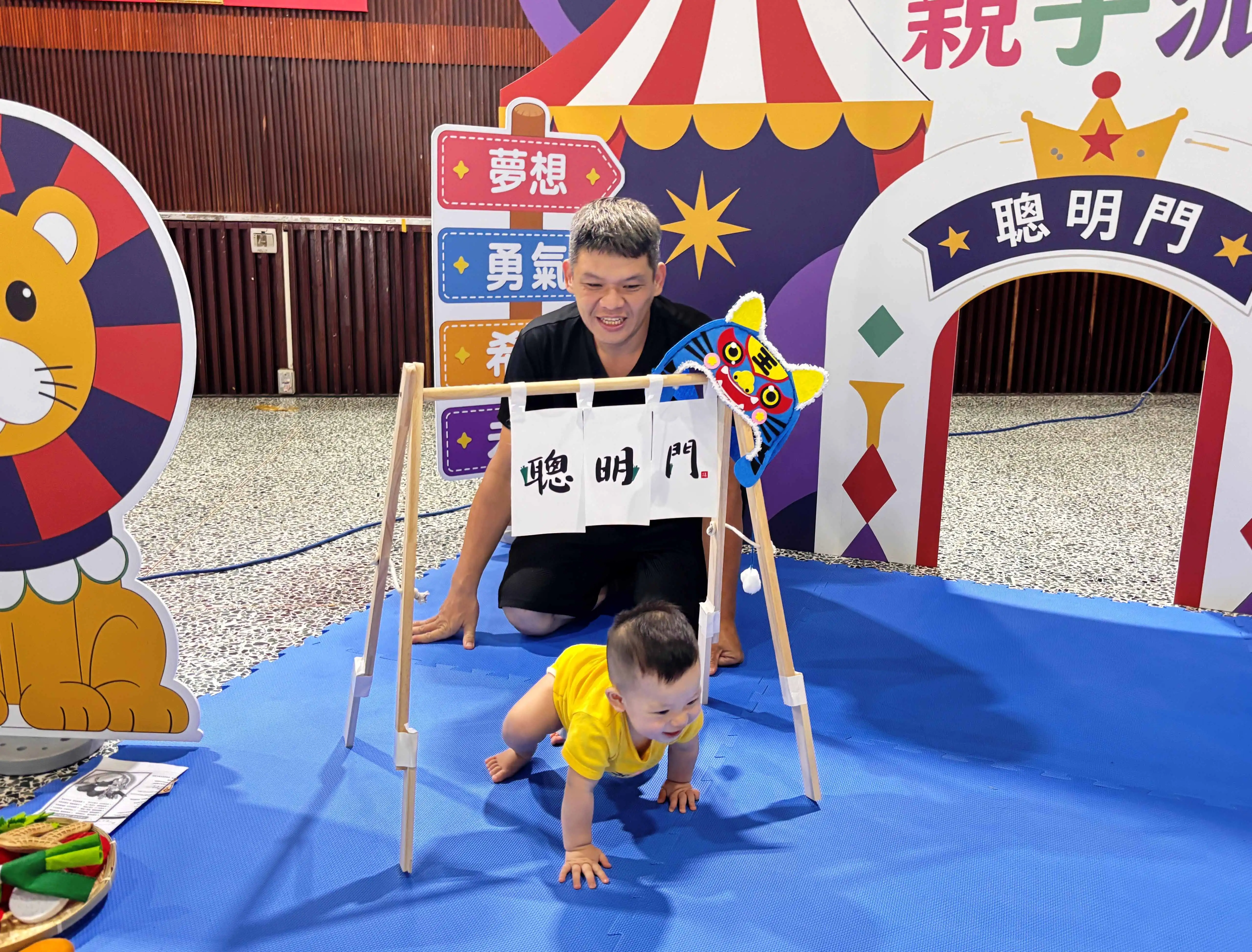 寶寶在家長陪伴下開心爬過象徵祝福的「聰明門」，萌趣模樣為「童伴台南・寶寶抓周親子派對」增添歡樂氣氛。（台南市社會局提供）
