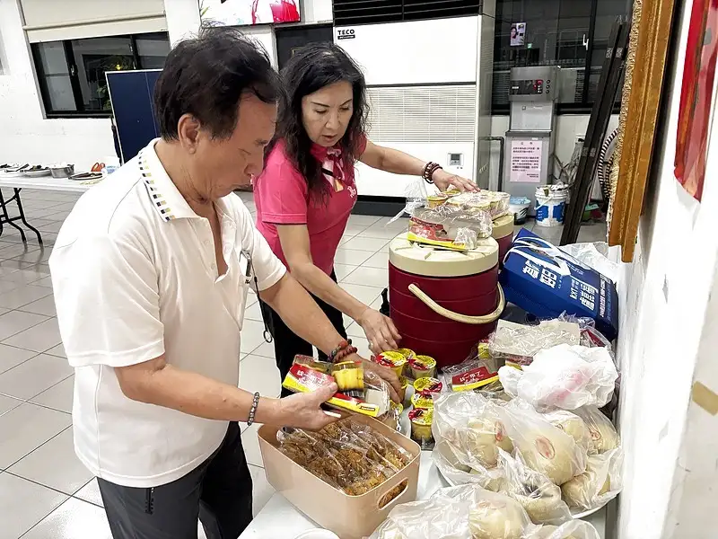 南都里里長高麗雲與居民共同整理餐點，為「一人一道菜」共餐活動做準備。（記者 范繼如攝）