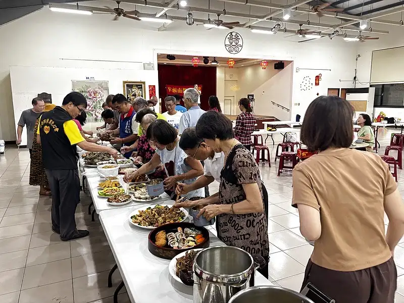 南都里舉辦「一人一道菜」共餐活動，居民分享各自準備的拿手料理，藉由美食交流凝聚鄰里情感。（記者 范繼如攝）