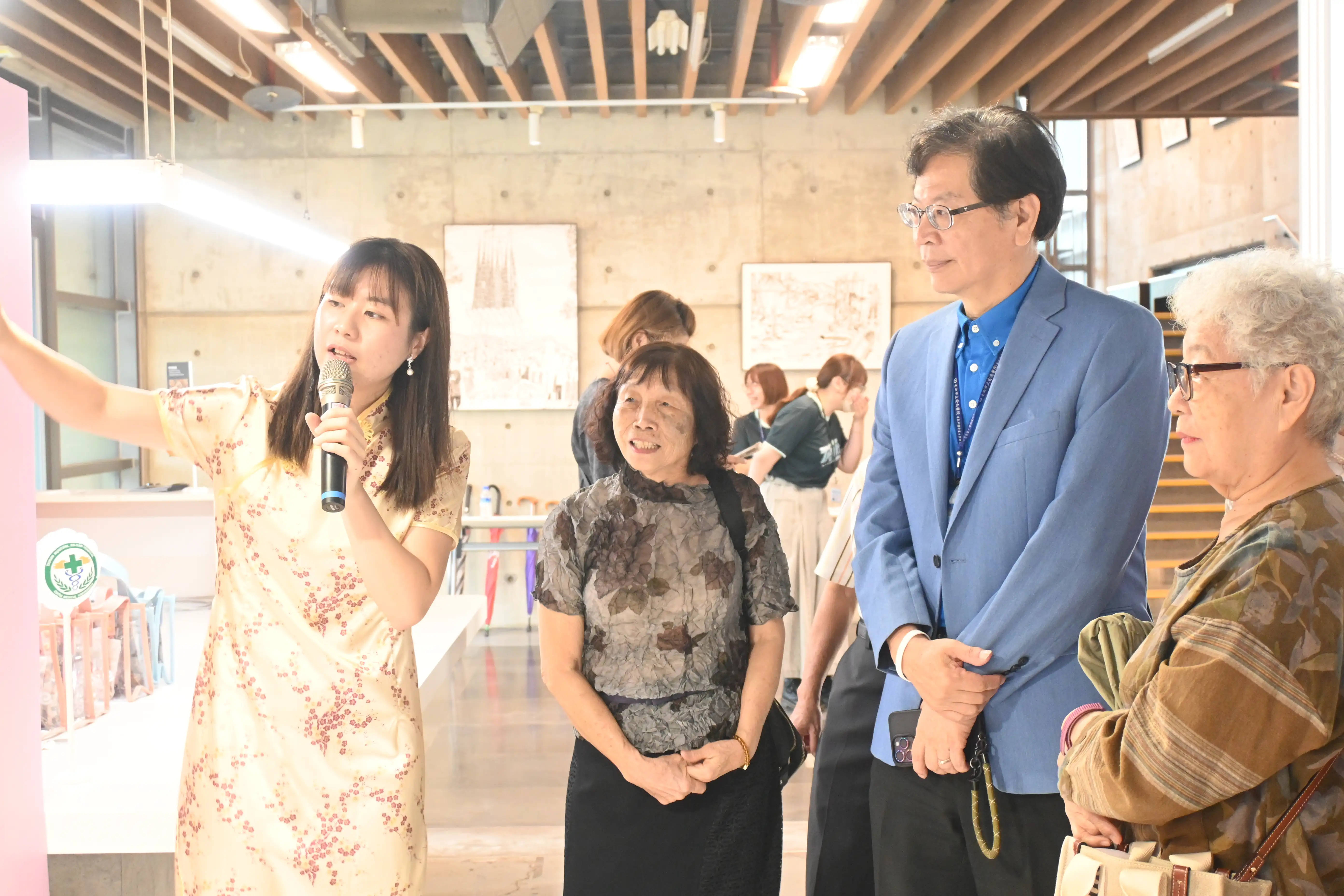 安南醫院社區護理師(左一)帶領來賓參觀展覽，透過旗袍拼貼與懷舊場景，介紹長者創作背後的生命故事及社區失智友善推動成果。(圖/安南醫院提供)
