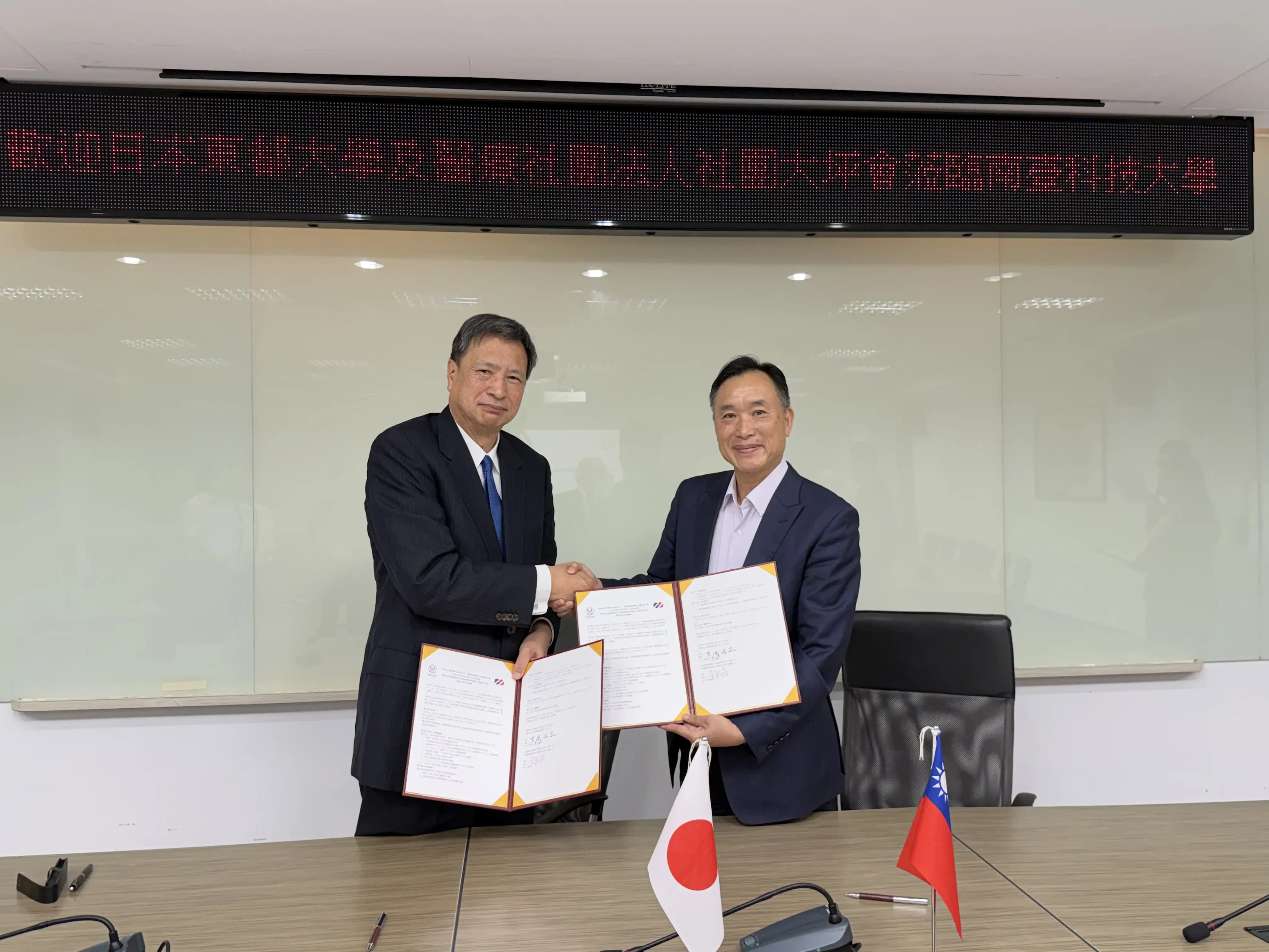 南臺科大校長黃能富(右)與東都大學校長吉岡俊正(左)共同展示簽署之合作協議書。(圖/ 南臺科大提供)