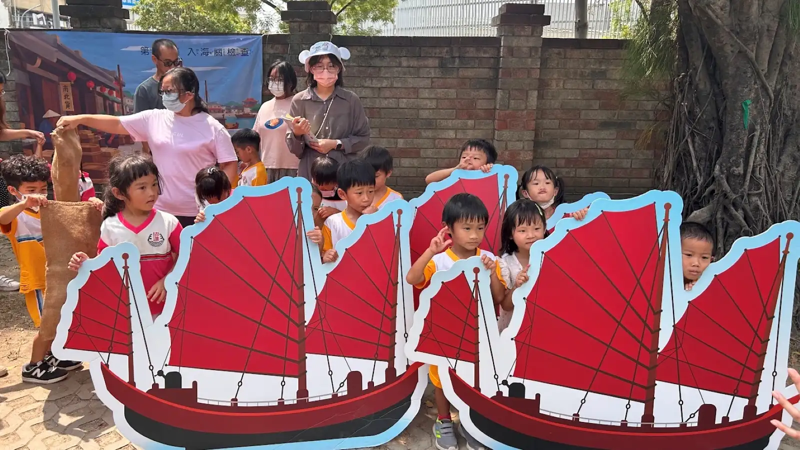 幼兒合力搬運大型貨船模型，模擬昔日貨船駛入台南運河、進行入關查驗的情景。(圖/南台科大提供)