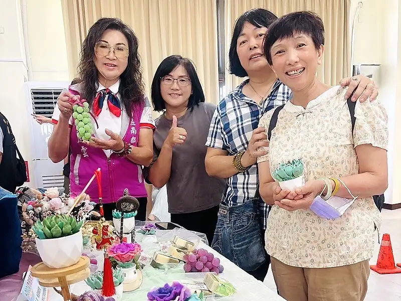 南都里里長高麗雲與來賓於成果展攤位合影，葡萄、花卉及多肉植物造型手工皂，展現學員巧思。（圖／記者范繼如攝）