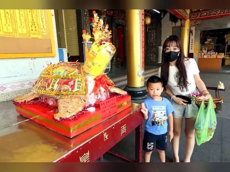 信眾帶著孩子到開基玉皇宮參拜，廟內擺放平安龜等祝壽供品。（圖／記者范繼如攝）