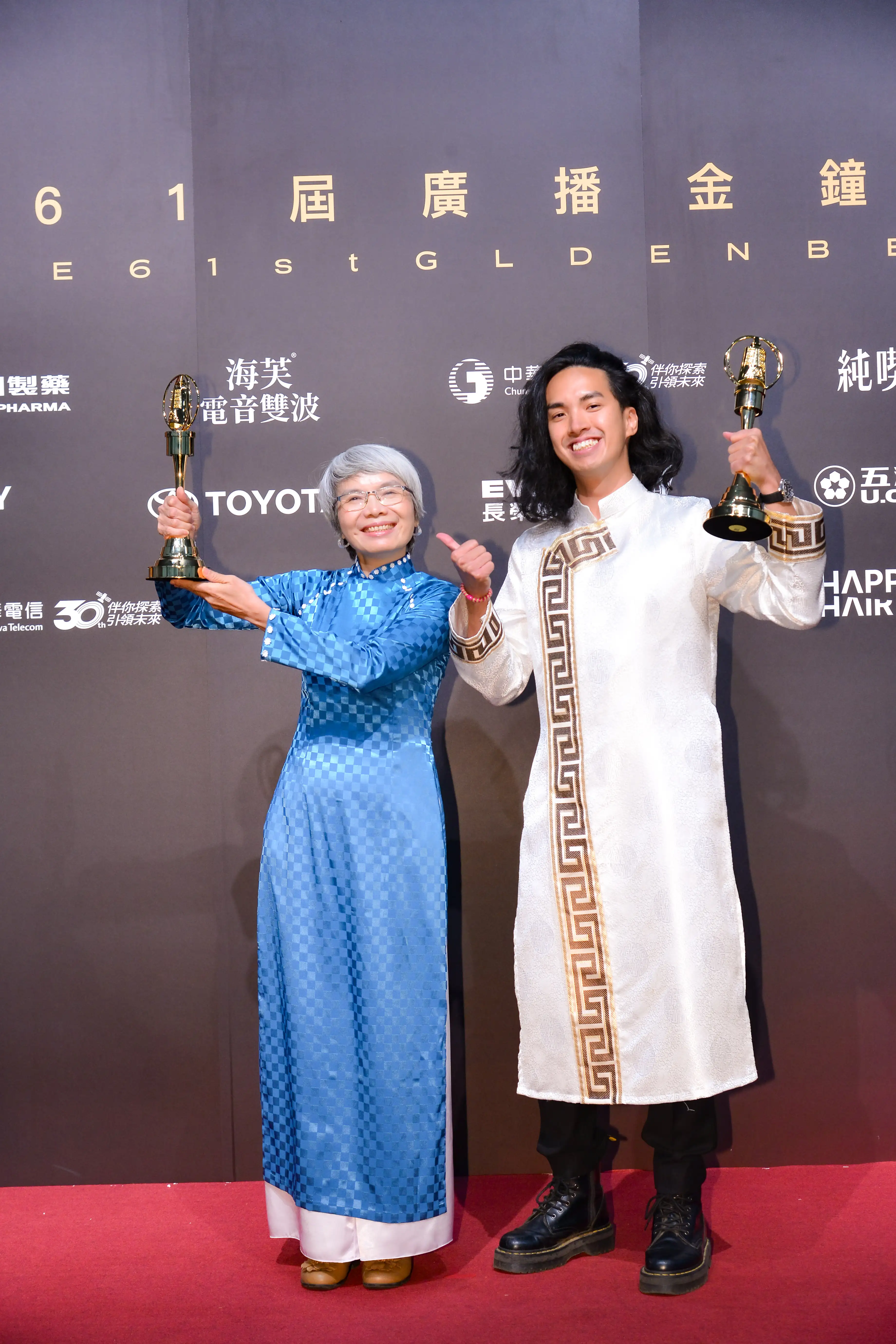 高雄廣播電臺《愛家好姐妹》節目榮獲第61屆廣播金鐘獎「生活風格節目獎」，主持人阮氏貞（左）身著傳統服飾與陳德民（右）開心高舉金鐘獎座。（圖／高雄市新聞局提供）