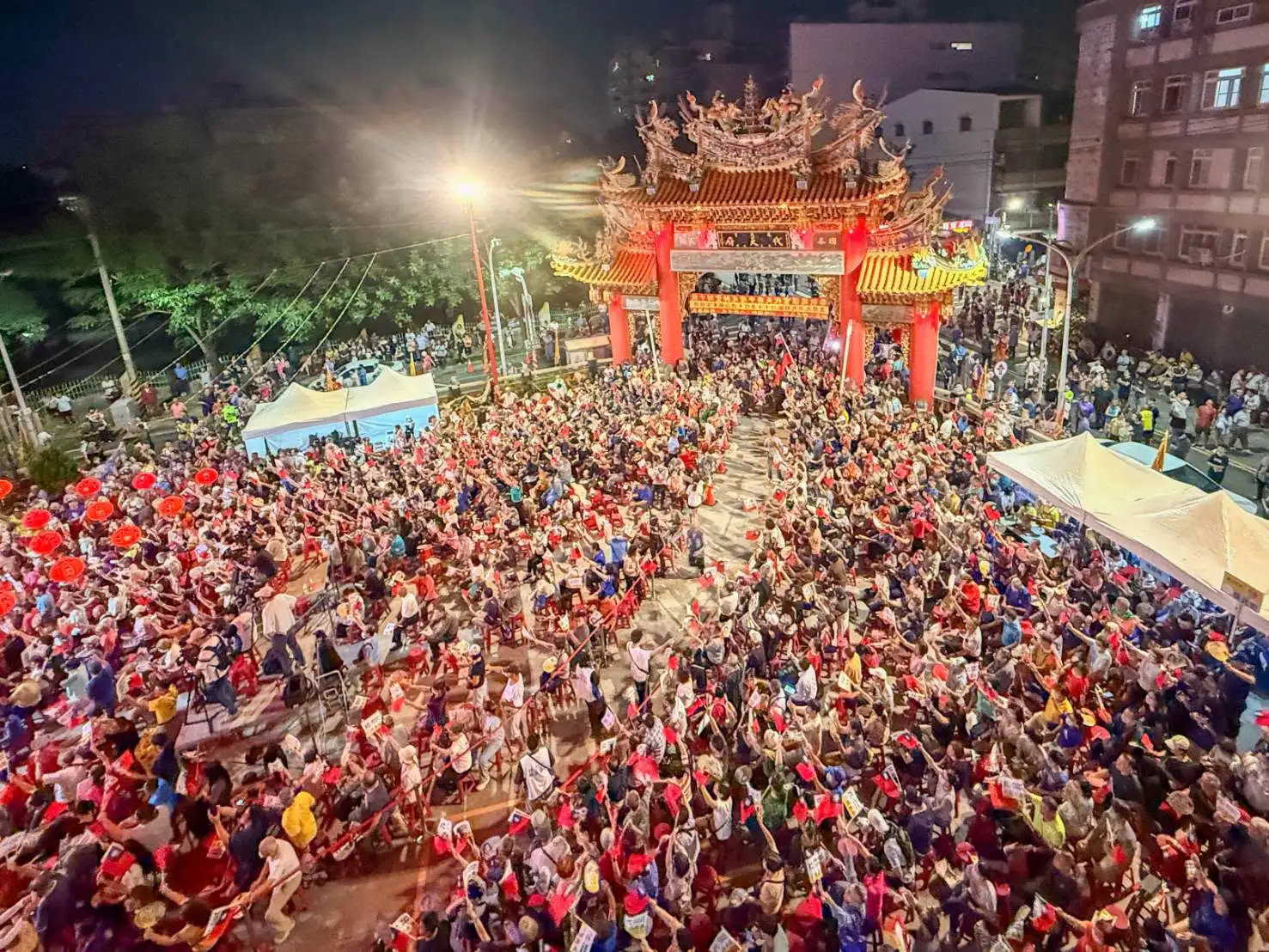這張照片為柯志恩與韓國瑜在小港鳳儀宮代天府「廟口開講」現場的俯瞰空拍全景，廟埕與牌樓周邊湧入滿滿的支持群眾與國旗海。   依據新聞編採規範，為您提供以下幾種規格的圖說：標準新聞圖說（首選推薦，適合刊登於報導首圖）：國民黨高雄市長候選人柯志恩17日晚間於小港鳳儀宮代天府舉辦廟口開講，現場湧入大批支持鄉親擠爆廟埕，氣氛熱烈。（圖／柯志恩團隊提供）
