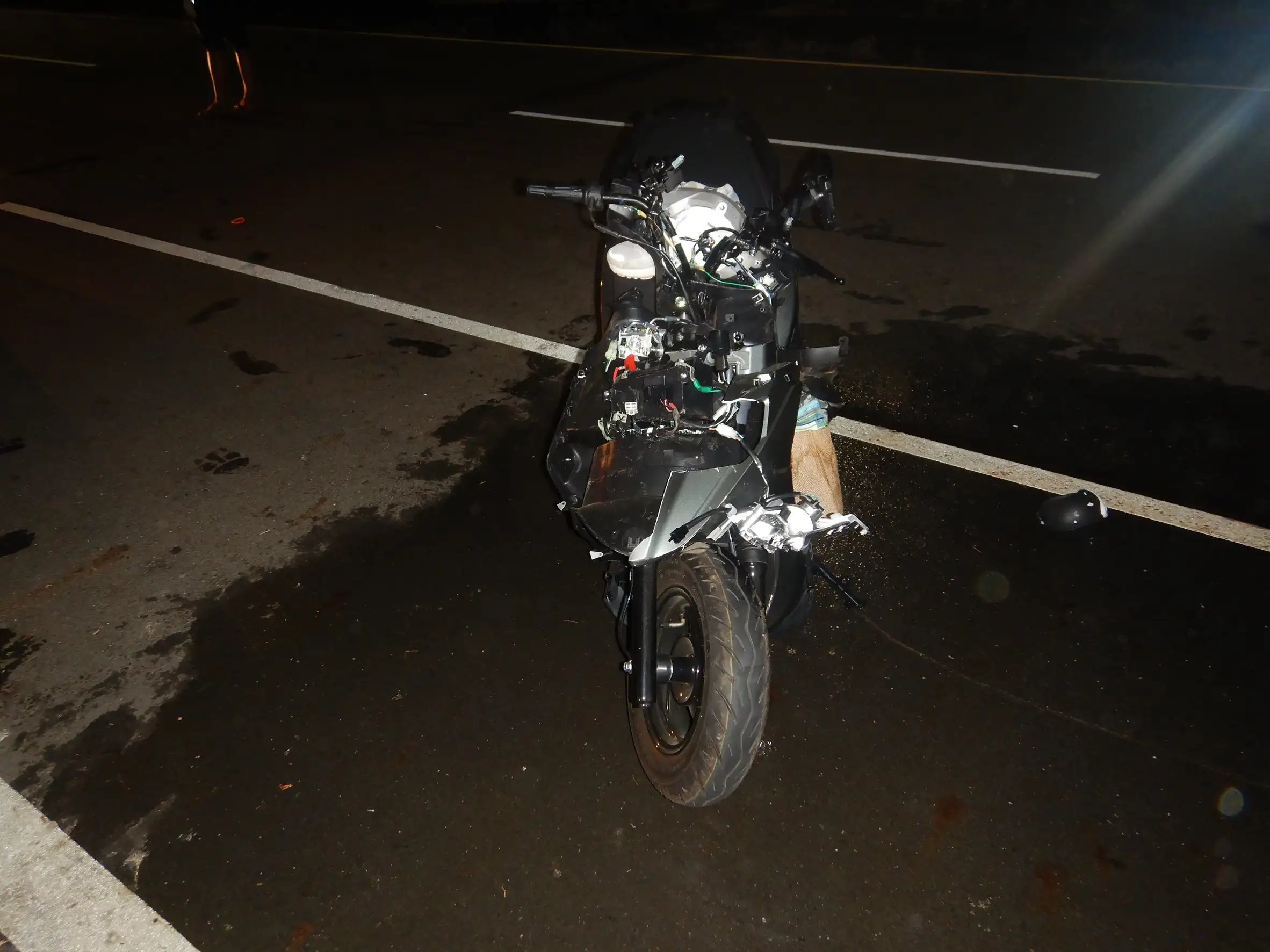 涉案重機車車頭遭劇烈撞擊全毀、零件外露碎裂一地，女騎士傷勢嚴重當場失去生命跡象，確切肇因由警方深入調查。(圖 / 張振興翻攝)