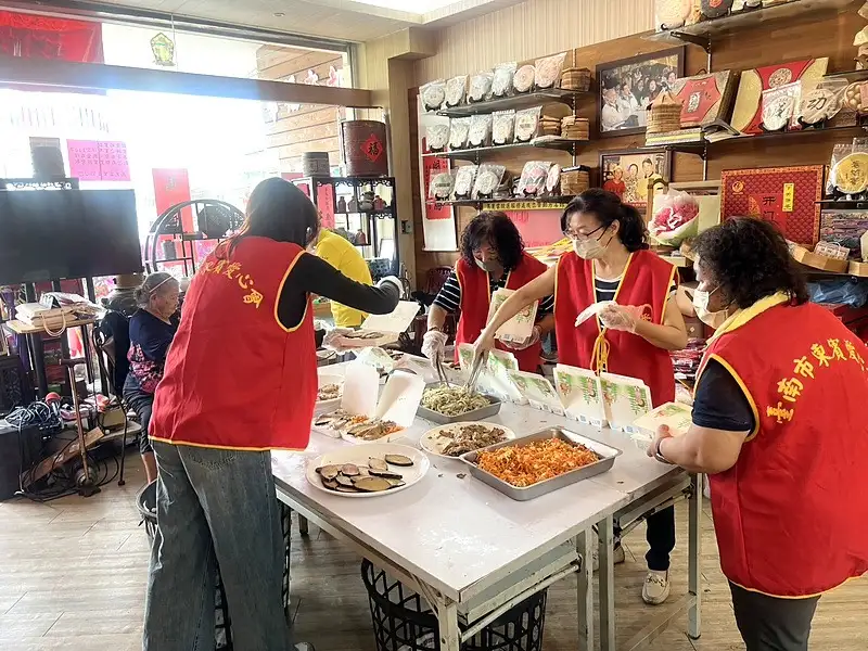 志工分工合作，將一道道菜餚裝入餐盒，齊力完成本月120份愛心便當。（圖/記者范繼如攝）