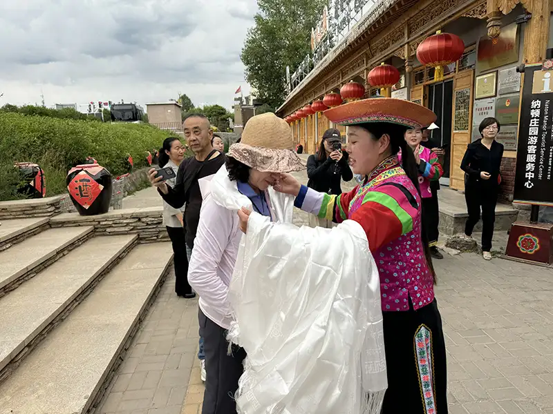 來到納頓莊園，進門時土族婦女獻上哈達，來表達對貴客最高貴的禮節。(記者李帆純攝)