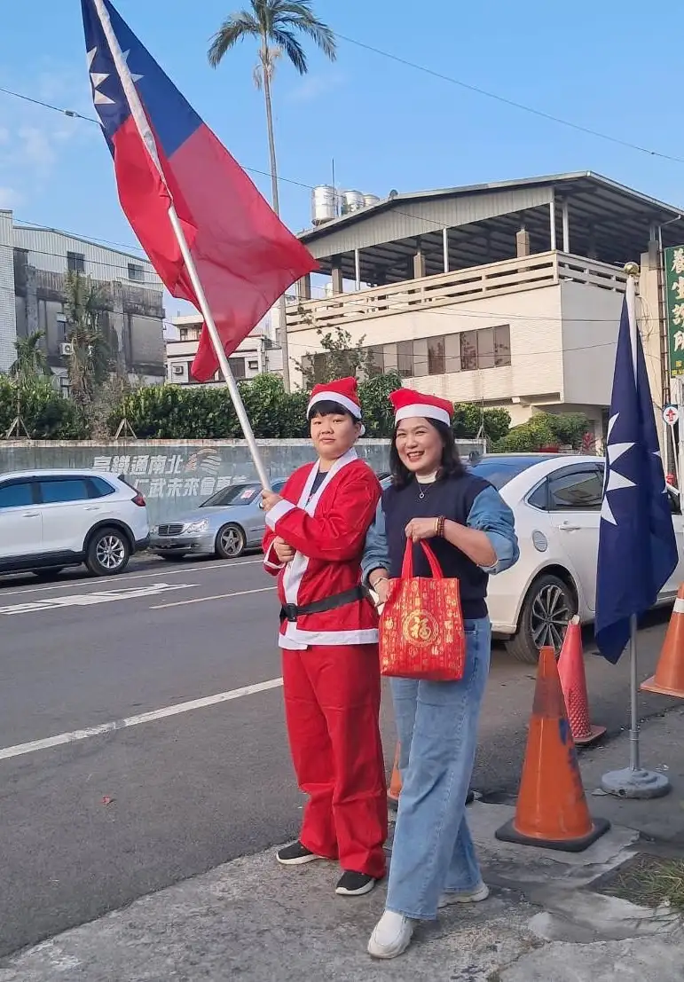 前市議員陳若翠扮聖誕老人 揮舞國旗慶祝行憲紀念日，並快閃迎接下課的小朋友發送耶誕禮物。（記者吳文欽攝）