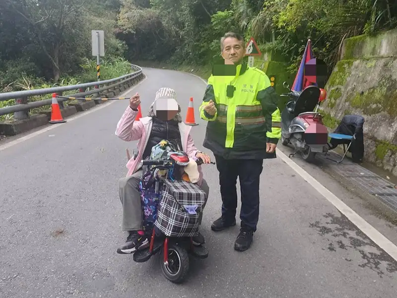 乘電動醫療代步車勇闖南橫圓夢的張姓阿嬤，右腳截肢領有身心障礙手冊，由台東霧鹿派出所胡松所長一路陪同至安全道路，阿嬤感動的握著所長的手，一再致謝。（記者洪淑玉翻攝）