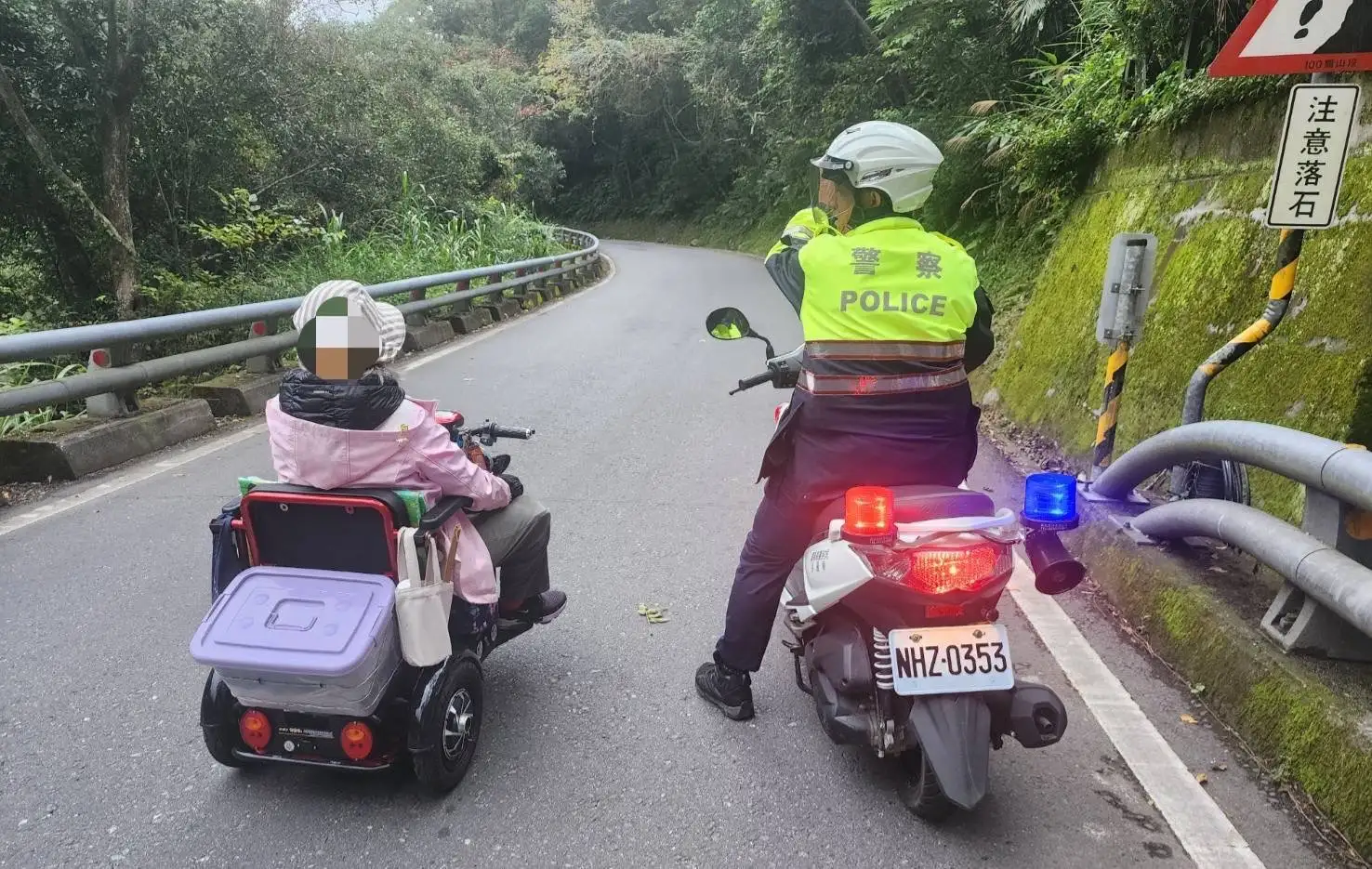 乘電動醫療代步車勇闖南橫圓夢的張姓阿嬤，右腳截肢領有身心障礙手冊，由台東霧鹿派出所胡松所長一路陪同至安全道路，阿嬤感動的握著所長的手，一再致謝。（記者洪淑玉翻攝）