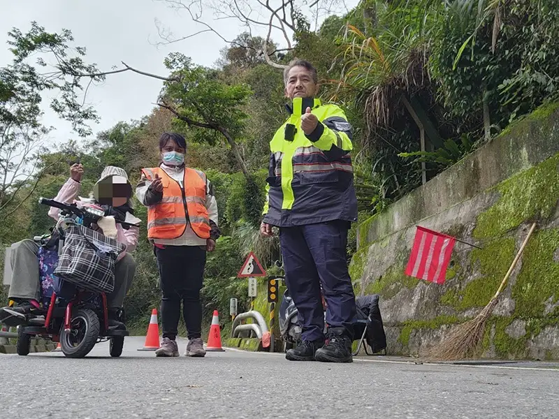 乘電動醫療代步車勇闖南橫圓夢的張姓阿嬤，右腳截肢領有身心障礙手冊，由台東霧鹿派出所胡松所長一路陪同至安全道路，阿嬤感動的握著所長的手，一再致謝。（記者洪淑玉翻攝）