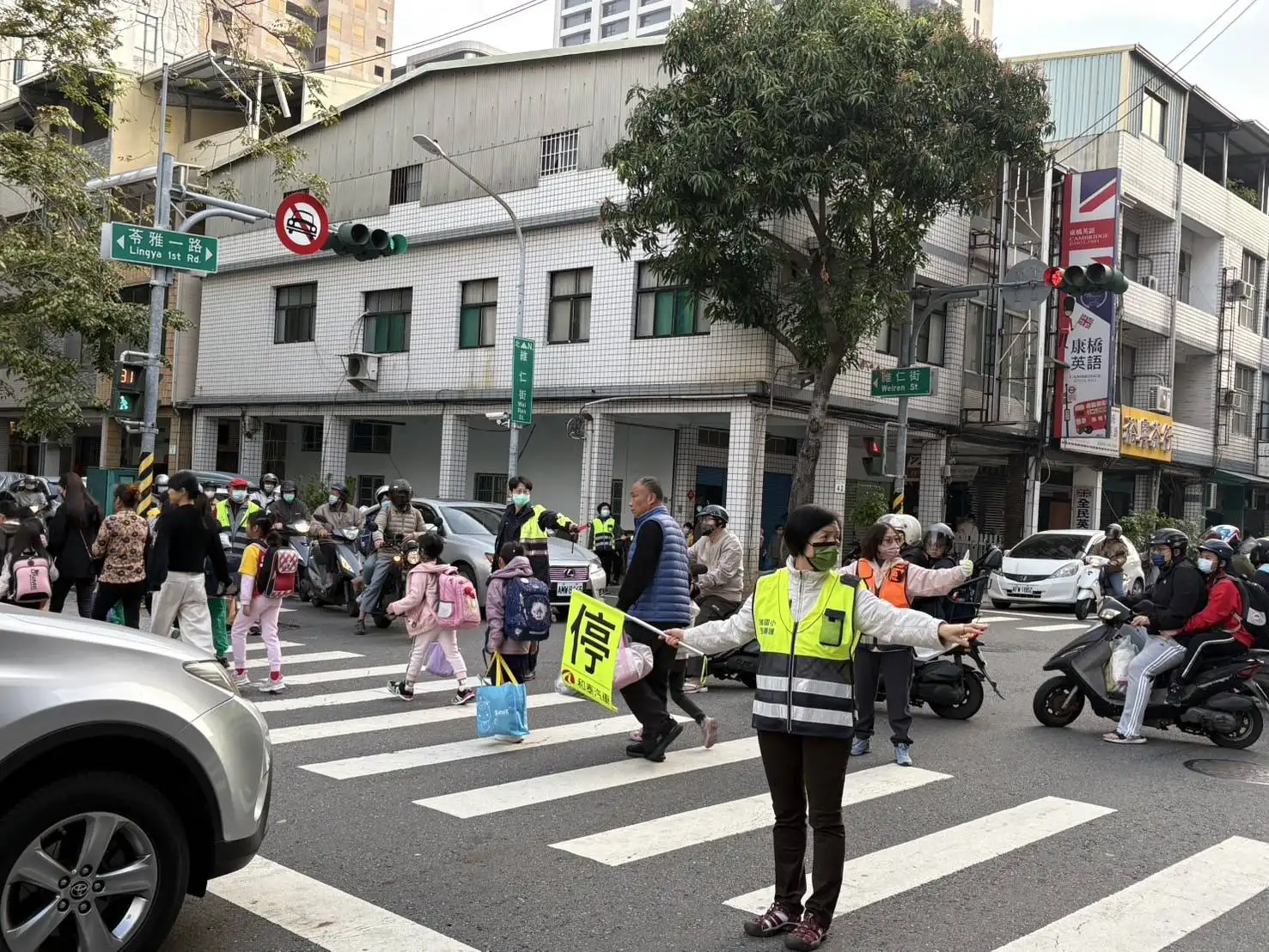 員警路口引導學童和家長安全穿越斑馬線，確保上學時段交通安全。(圖/高雄市婦幼隊提供)