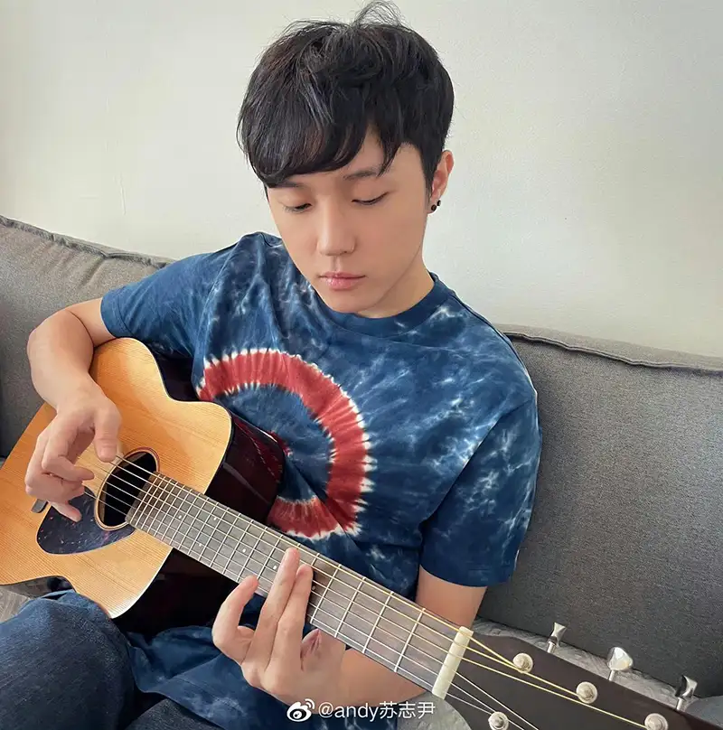 蘇志尹在家中沙發上專注彈奏吉他,享受靜謐的創作時刻。(蘇志尹提供)