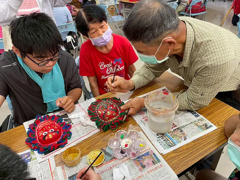 謝俊煌老師耐心教導大學生與長輩製作面具的技巧。(圖/嘉南藥理大學 提供)