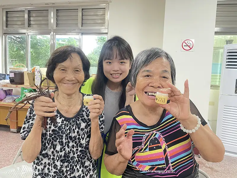 80歲楊阿嬤(左)開心在嘉藥學生協助下完成丹參萬金膏。(圖/嘉藥藥學系 提供)