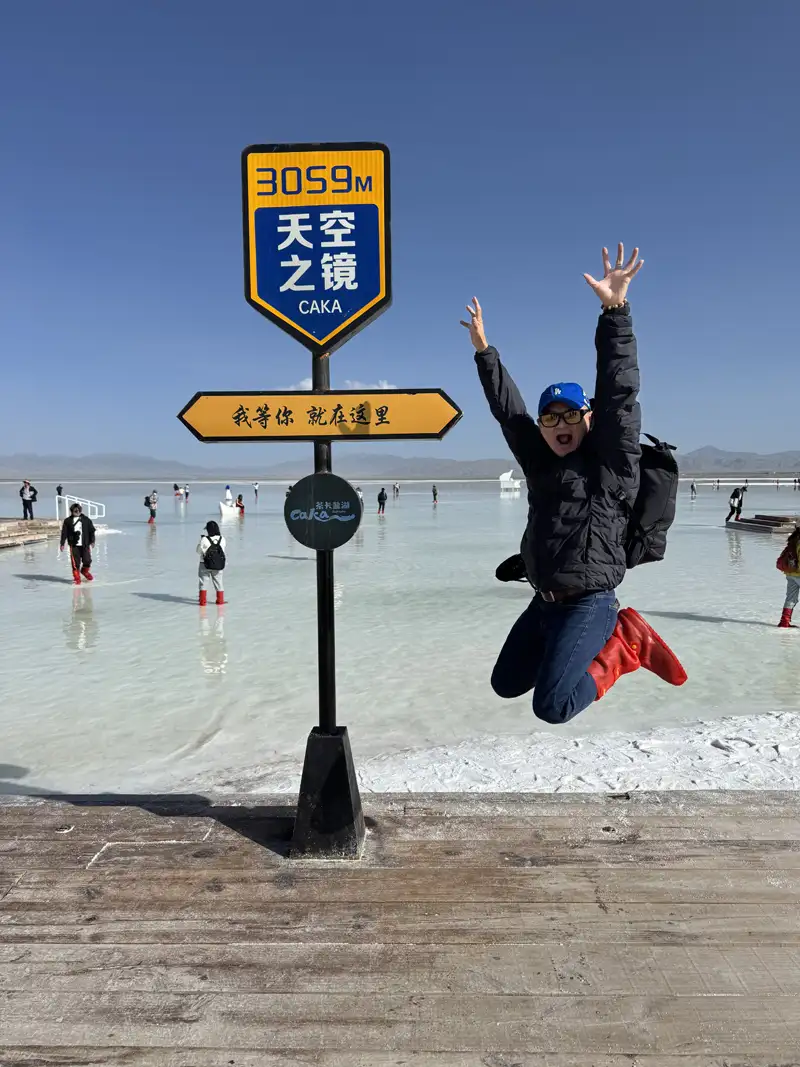 旅人在茶卡鹽湖「天空之鏡」地標前躍起留影,藍天、陽光與潔白鹽湖交織出如夢似幻的畫面,定格旅途中最純粹歡樂的一刻。(記者駱薇合攝)