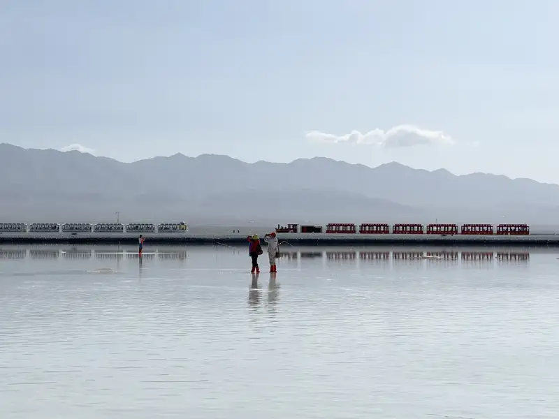 茶卡鹽湖上的觀光小火車沿著湖畔前行,映照在如鏡湖面之上,遠山、雲影與旅人交織成一幅靜謐美景。(記者駱薇合攝)