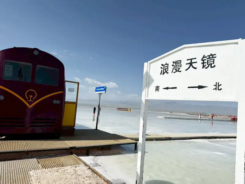 茶卡鹽湖景區內設有「浪漫天鏡」招牌與觀光小火車,搭配如鏡的湖面與遠山天際,彷彿走入宮崎駿神影少女場景。(記者駱薇合攝)