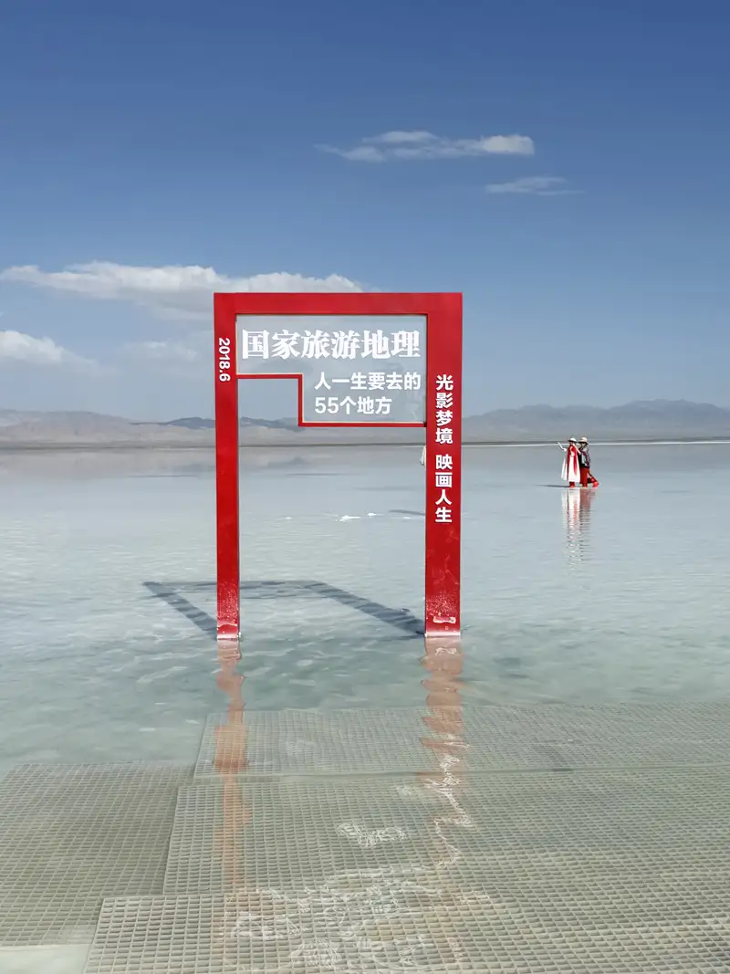 茶卡鹽湖設有「國家旅遊地理」紅色打卡框,映照天空與湖面,成為旅人拍照留念的熱門地標。(記者駱薇合攝)