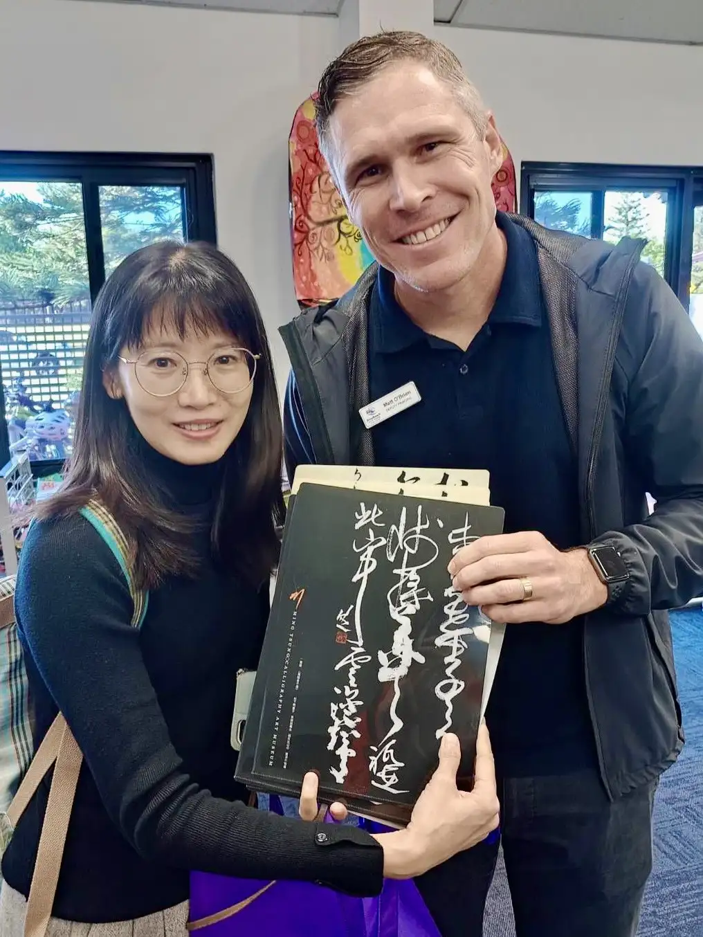 明宗國小蘇美琪老師特別準備明宗國小書法大師陳明德老師揮毫的資料夾,並把上面的古詩翻譯成英文,致贈予澳洲昆士蘭州兩所學校的校長與主任。(明宗國小提供)