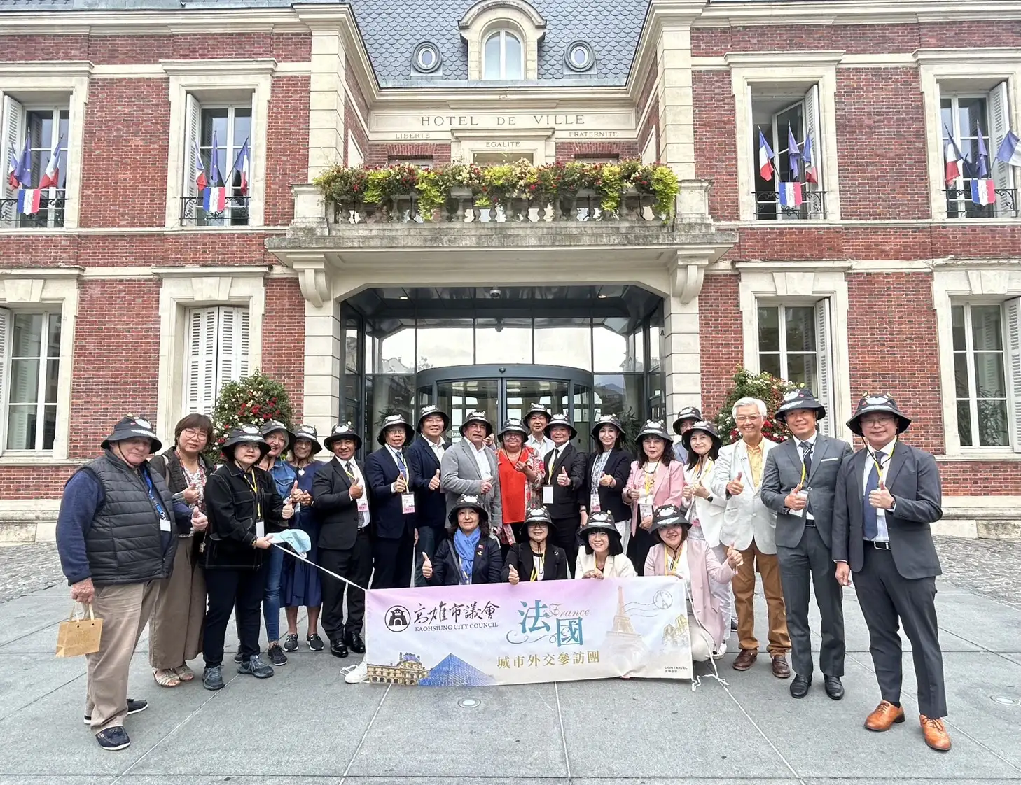 高雄市議會參訪團戴高雄熊漁夫帽,在法國大諾瓦西市政廳前合影。(高雄市議會提供)